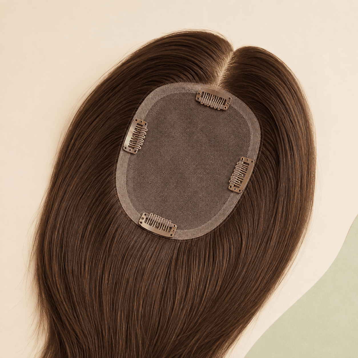 Flat-lay underside of a medium-brown human hair topper with an oval mono base and four inward-facing clips