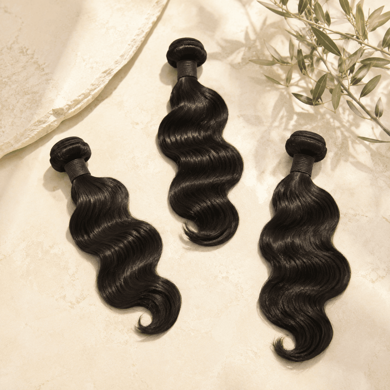 Three natural-black loose-wave human hair bundles arranged separately
